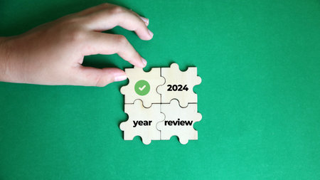 Hand put jigsaw puzzle piece with word 2024 YEAR REVIEW  on green backgroundの写真素材