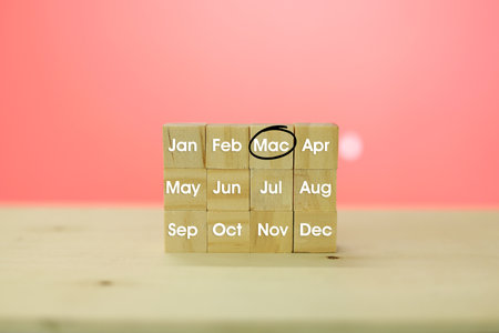 Wooden cube block with text monthly for one year on wood table and pink background.の写真素材
