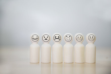 Wooden figures with smiley faces on a white background. Concept of customer satisfaction.の写真素材