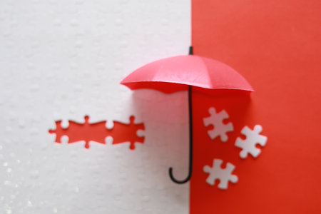 Umbrella and jigsaw puzzle on red and white background.の写真素材
