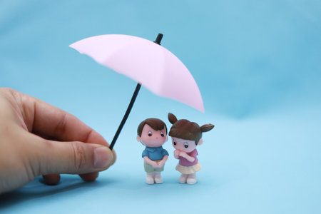 Little girl and boy under an umbrella on a blue background, close up