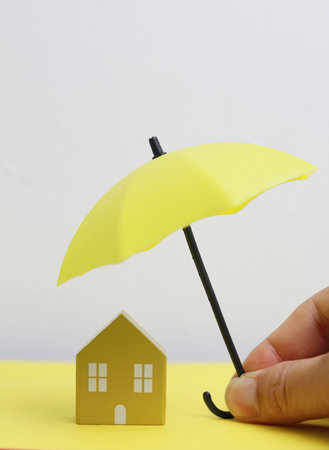 House and umbrella on yellow and white background. Concept of insurance.の写真素材