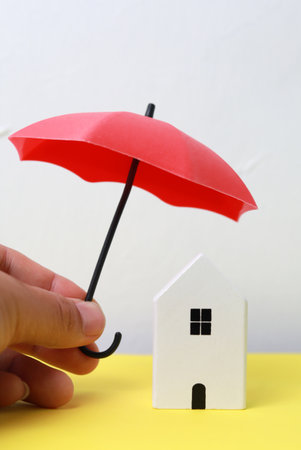 Conceptual image of insurance. House and umbrella in hand.の写真素材