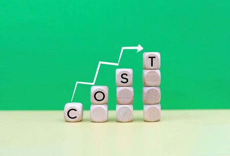 Wooden cubes with the word cost and arrow on a green background