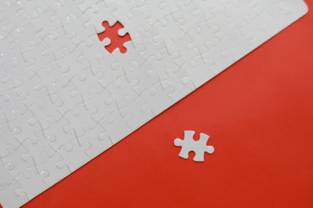 Close up white jigsaw puzzle with missing piece on red background.の写真素材