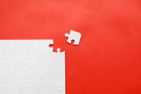 Top view of white jigsaw puzzle pieces on red background with copy space