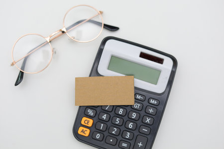 calculator with business card and eyeglasses on white background