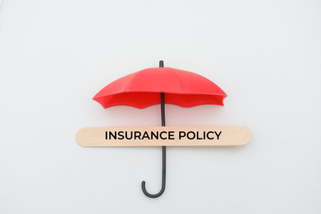 Insurance policy concept. Red umbrella and wooden sign on white backgroundの写真素材