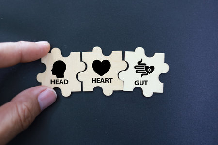 Business concept image of two puzzle pieces connecting to each other with heart symbol over black...