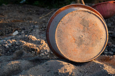 the bottom of the orange bucket is on the sand for home renovation needs at early morningの写真素材