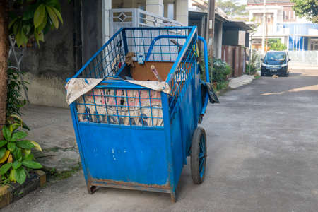 Depok, Indonesia - July 8th 2021 : A blue garbage cart is parked on the street in a residential area during the covid-19 pandemicのeditorial素材