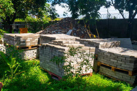 pile of paving blocks in the middle of a lush garden with green plantsの写真素材