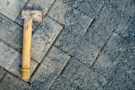 a small ax is placed on a paving block full of sand and gravel
