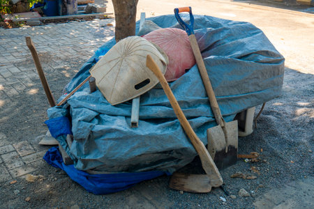 renovation equipment, hoe, garbage screw, neatly arranged wrapped in tarpaulin over the garden using paving blocksの写真素材