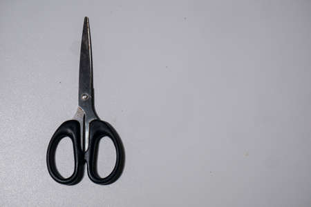 steel scissors with black handle photographed on a white backgroundの写真素材