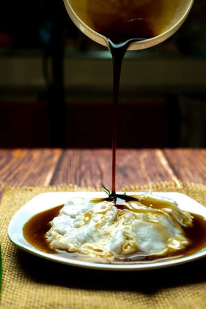 Sweet and delicious brown sugar syrup pouring on a porridge, bubur sumsum, indonesian traditional...