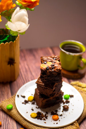 pile of chocolate brownies with a green cup of tea photographed on wood textured tableの写真素材