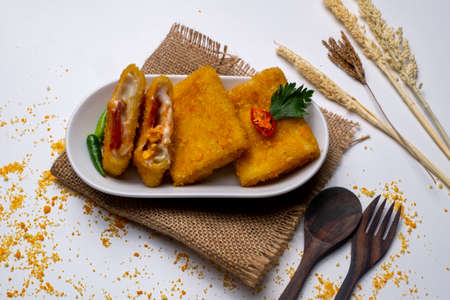 Risoles on white plate and decorated with cultery and green chilies on white tableの写真素材