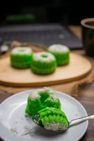 Putu ayu, Indonesian traditional food, with blurry pieces of Putu ayu on wooden cutting board, laptop and a cup of coffeeの写真素材