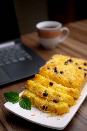 Cake-tape with cheese, Indonesian traditional food, a black laptop, a cup of tea