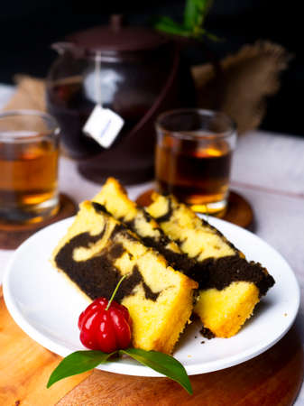 Marmer Cake, Indonesian Food, on white plate with a cup of tea as backgroundの写真素材