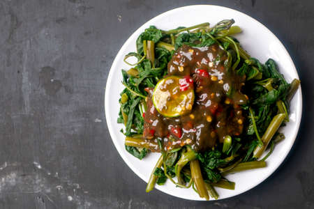 Petis kangkung with lemon, Indonesian Tradional Food from Semarang City on white plate and black...