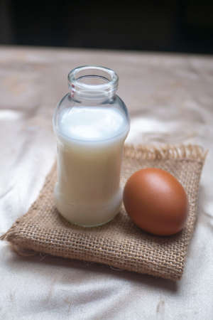 A bottle of milk and an egg on gold clothの写真素材