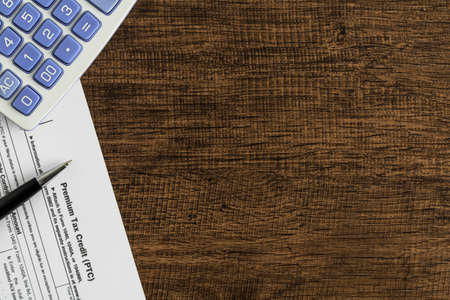 Premium tax credit form with calculator and pen on the wooden table