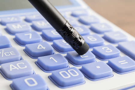 Pushing calculator number button with pencilの写真素材