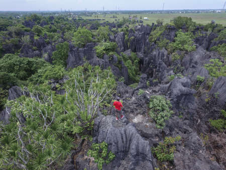Man with red shirt climb and hiking in the Forest of Rock (Hutan Batu) in Rammang Rammang - South...