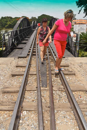 KANCHANABURI, THAILAND - JUNE15: Two unidentified women foreign tourists walking on the bridge over the river Kwai on JUNE15, 2012 Kanchanaburi, Thailandのeditorial素材