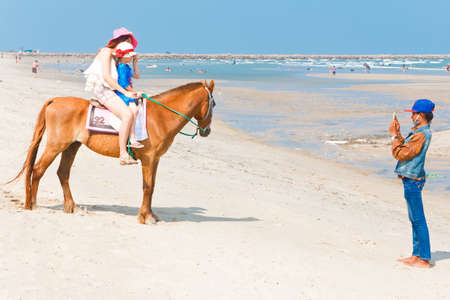 Phetchaburi, Thailand - March 28: Unidentified family tourists, enjoy Activities, riding horses, on cha-am beach on March 28,2015 in Petchaburi Thailand.のeditorial素材