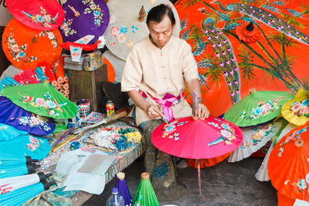CHIANG MAI, THAILAND - JANUARY 19: Unidentified man drawing flowers on paper umbrella, in traditional umbrella factory (Ban Boa -Sang) on January 19, 2014 in Chiang Mai, Thailand.のeditorial素材