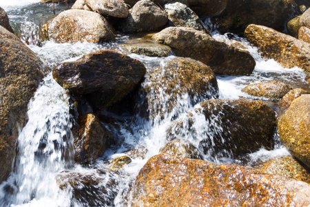 Water flowing over rocks in a stream, closeup of photo.の写真素材