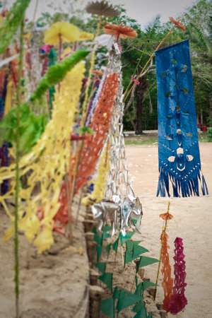 Multicolored Mon-style paper flags on a pile of sand, selective focus.