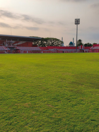 Football stadium with green grass and blue sky at sunset.