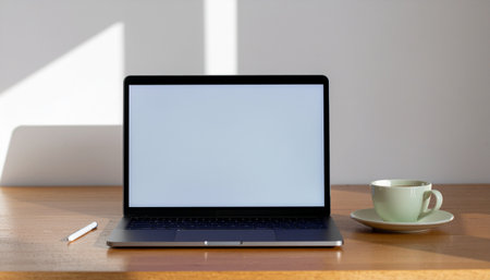 Laptop with blank screen and coffee cup on the wooden table.