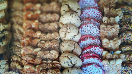 Rows of delicious freshly baked cookies with nuts and chocolate chips displayed on counter in bakery