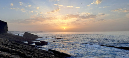 Golden sunrise illuminates atlantic ocean with rocky coastline and fisherman Casablanca in morocco