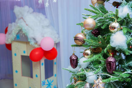 Christmas toys on a fir-tree. Gold and red colors in a close up decorated tree with interior backgroundの写真素材