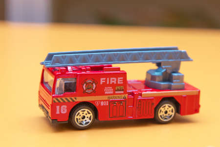 Red toy fire truck / Toy fire engine extinguishes flaming house. Careless handling of fire dangerous for lifeの写真素材