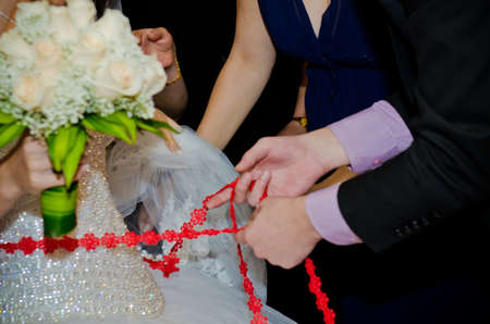 Close the ribbon on the belly of the bride. Women's fees on the wedding day.の写真素材