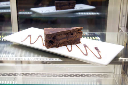 Pouring chocolate sauce on piece of chocolate cake . cake truffle with black chocolate sauceの写真素材