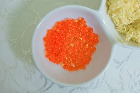 Red caviar in a little bowl on a white background. above view of red dyed salty caviare of halibut fish in glass jar isolated on white backgroundの写真素材