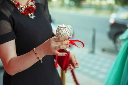 The girl decorated with a decorative candlestick in her hands and a sign . holds a candle in her...