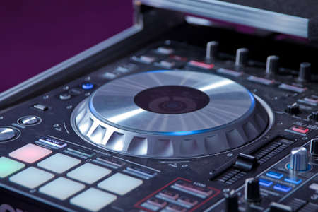 Dj mixes the track in the nightclub at party . Headphones in foreground and DJ hands in motion