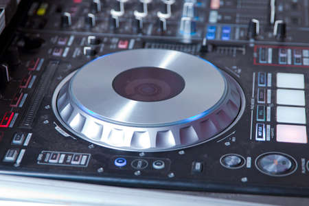 Dj mixes the track in the nightclub at party . Headphones in foreground and DJ hands in motion