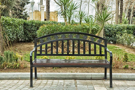 Black bench on the street . Bench in Park on a background of brick green treeの写真素材
