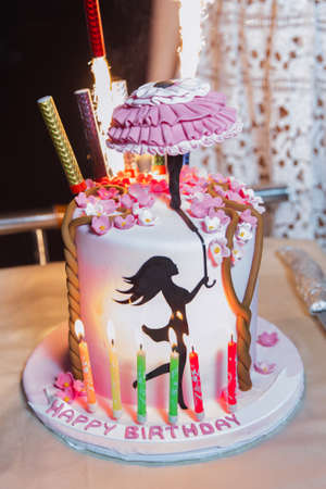 A birthday cake with a silhouette of a girl holding an umbrella in her hand decoration