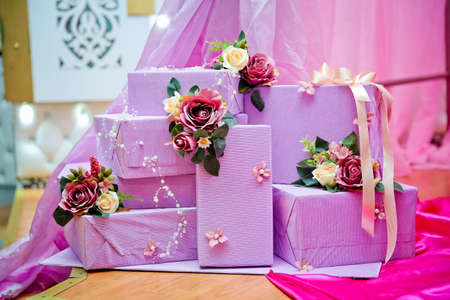 Stack of violet gift boxes . Purple gift boxes with white and red flowersの写真素材